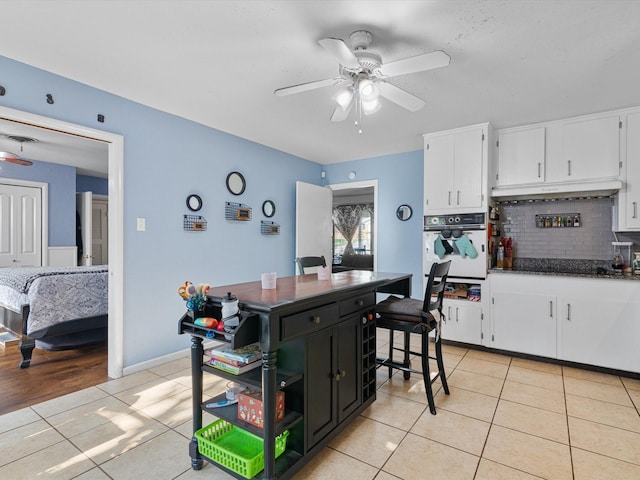 kitchen featuring light tile patterned floors, ceiling fan, white cabinetry, tasteful backsplash, and oven