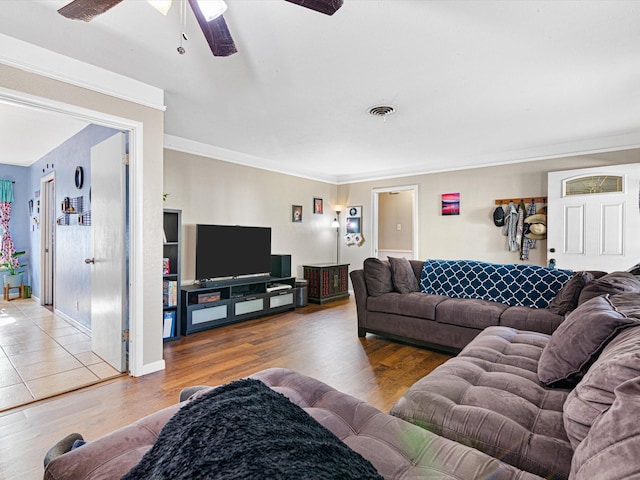 living room with wood-type flooring, ornamental molding, and ceiling fan