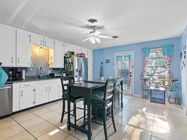 kitchen featuring appliances with stainless steel finishes, tasteful backsplash, white cabinetry, sink, and light tile patterned floors