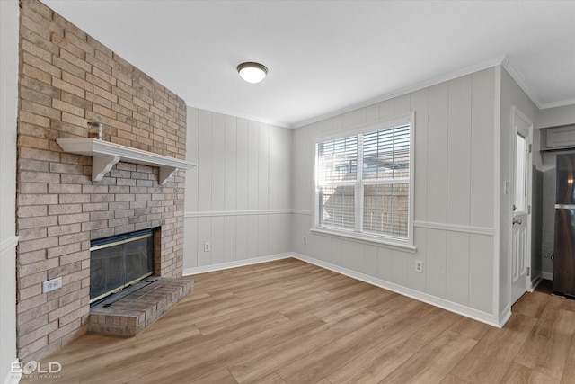 unfurnished living room featuring light hardwood / wood-style floors, ornamental molding, and a brick fireplace