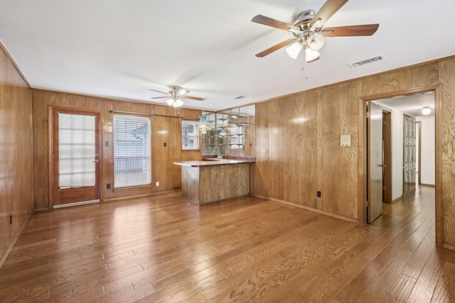 unfurnished living room featuring wooden walls, hardwood / wood-style floors, and ceiling fan