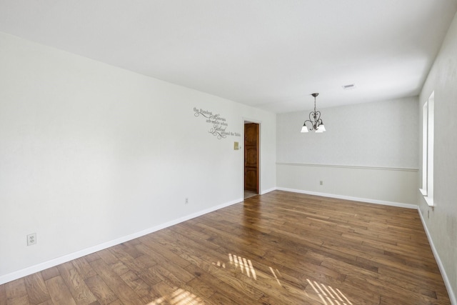 unfurnished room with hardwood / wood-style flooring and an inviting chandelier