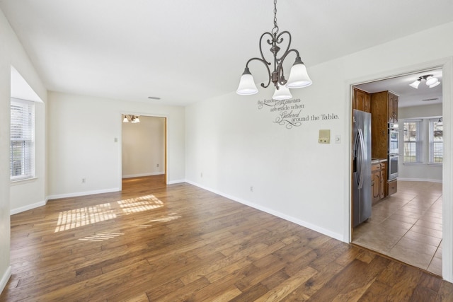 empty room with a chandelier and dark wood-type flooring