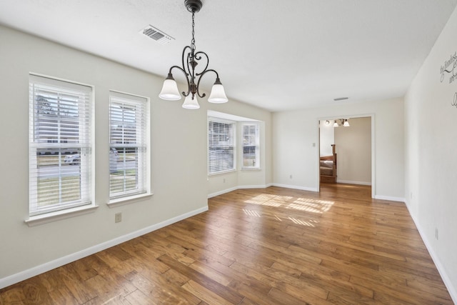 unfurnished dining area with wood-type flooring and a chandelier