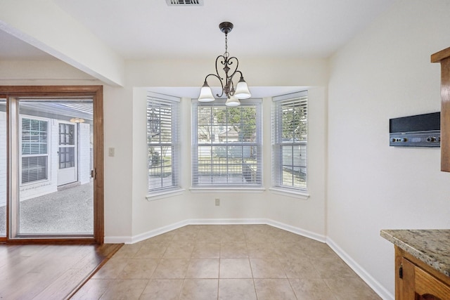 unfurnished dining area featuring light tile patterned floors and an inviting chandelier