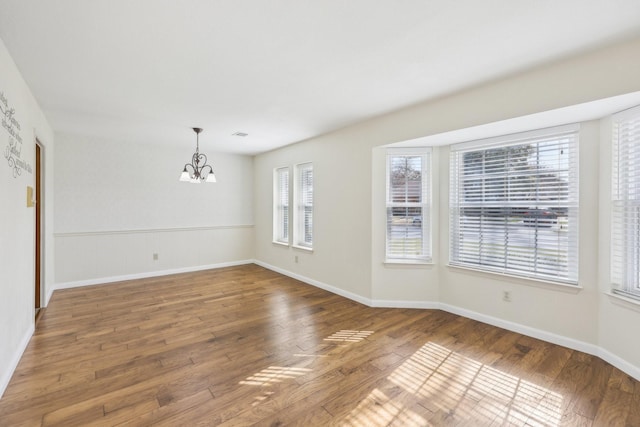 unfurnished room featuring wood-type flooring and an inviting chandelier