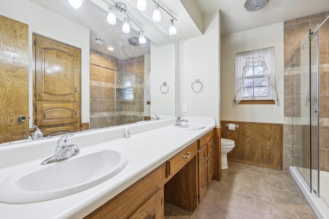 bathroom featuring vanity, wood walls, toilet, and a shower with door