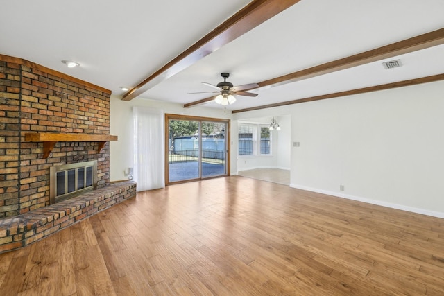 unfurnished living room with ceiling fan, beam ceiling, a fireplace, and light hardwood / wood-style flooring