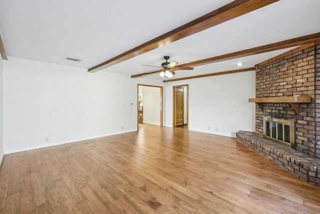 unfurnished living room with ceiling fan, beam ceiling, light wood-type flooring, and a fireplace