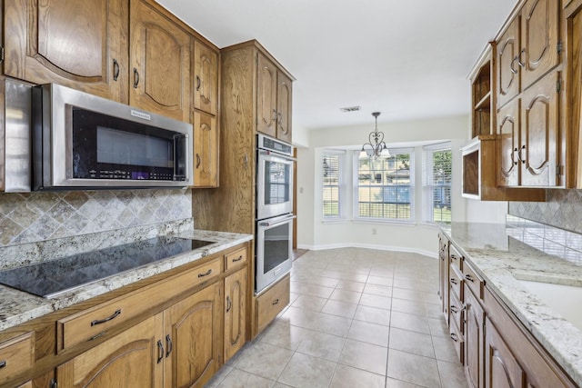 kitchen featuring light tile patterned floors, backsplash, stainless steel appliances, and hanging light fixtures