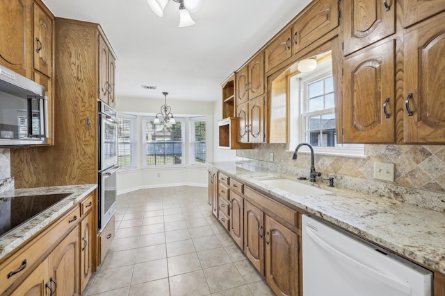 kitchen with sink, stainless steel appliances, backsplash, pendant lighting, and light tile patterned floors