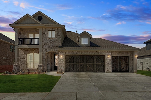 view of front of house with a garage, driveway, a balcony, and brick siding