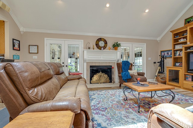 living room with a fireplace, ornamental molding, wood-type flooring, vaulted ceiling, and french doors