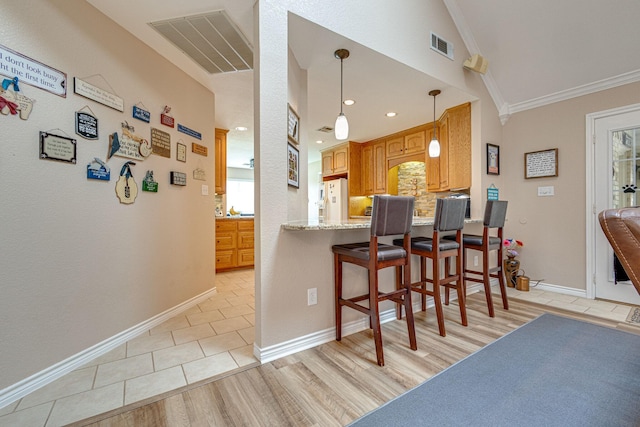 kitchen featuring light stone counters, ornamental molding, a kitchen breakfast bar, kitchen peninsula, and white refrigerator with ice dispenser