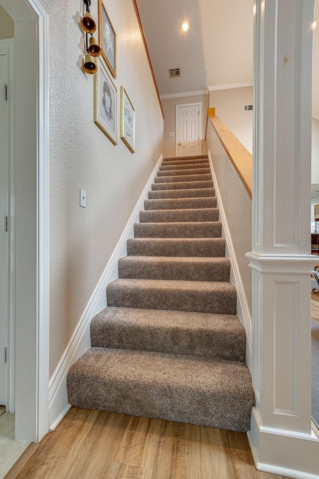 stairs with hardwood / wood-style flooring and ornamental molding