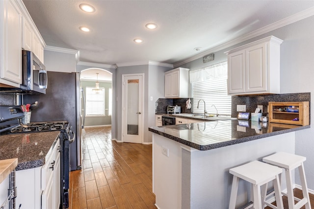 kitchen featuring a kitchen bar, white cabinetry, kitchen peninsula, and range with gas cooktop