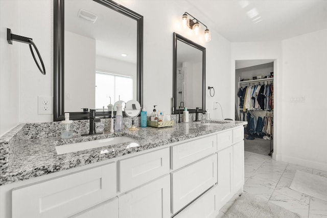 full bath with double vanity, marble finish floor, baseboards, and a sink