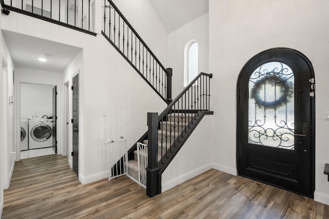 foyer entrance featuring washing machine and dryer, a towering ceiling, baseboards, stairway, and dark wood-style floors