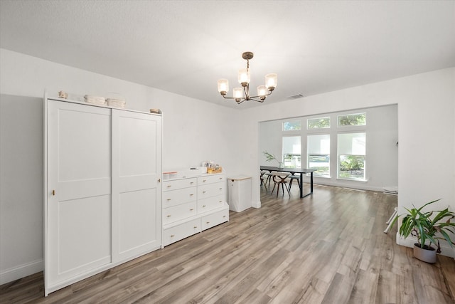 unfurnished dining area with a chandelier, light wood-type flooring, visible vents, and baseboards