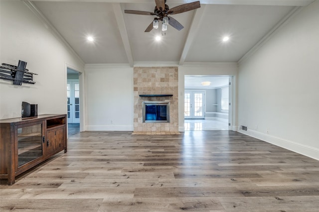 living room with vaulted ceiling with beams, ceiling fan, light wood-type flooring, and a tile fireplace