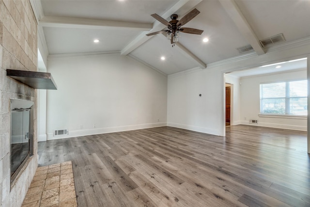 unfurnished living room with ceiling fan, crown molding, wood-type flooring, lofted ceiling with beams, and a fireplace