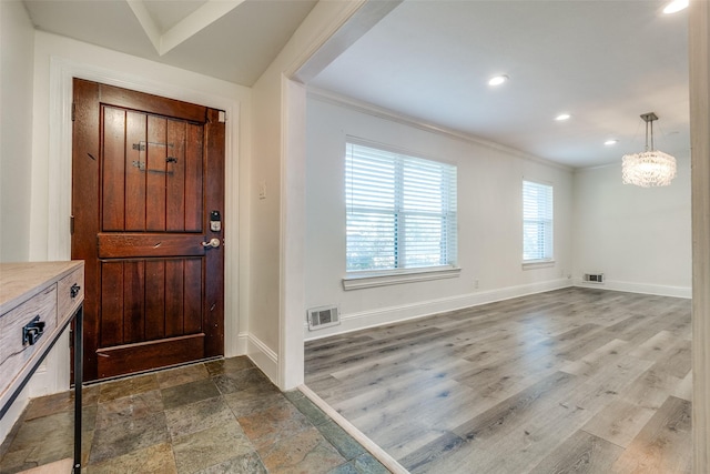 entrance foyer with ornamental molding and a notable chandelier