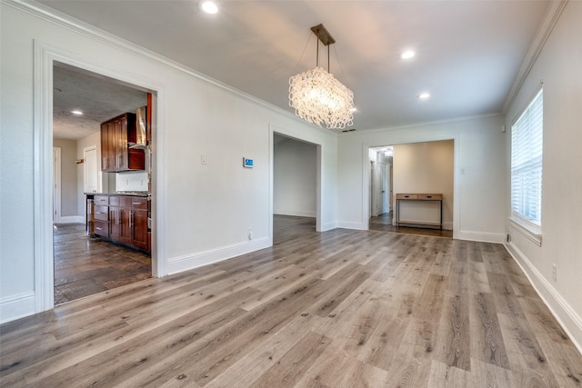 interior space with an inviting chandelier, light hardwood / wood-style floors, and ornamental molding