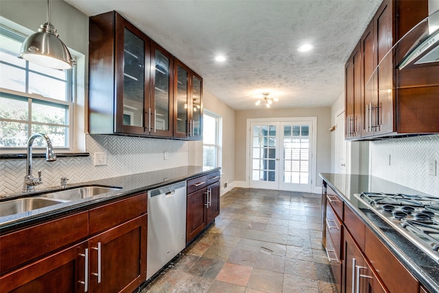 kitchen featuring backsplash, sink, a textured ceiling, decorative light fixtures, and stainless steel appliances