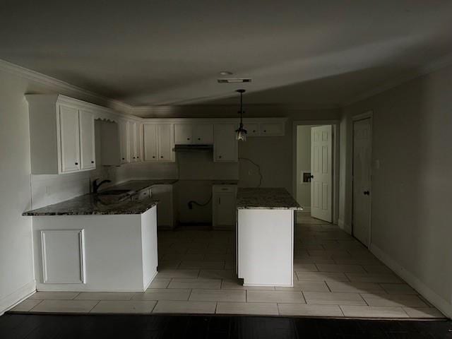 kitchen with sink, white cabinetry, hanging light fixtures, dark stone countertops, and a center island