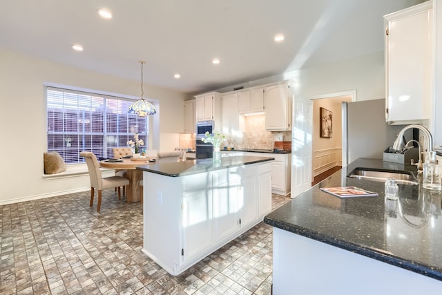 kitchen with stainless steel microwave, sink, white cabinets, and a chandelier