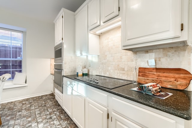 kitchen with white cabinets, decorative backsplash, stainless steel appliances, and dark stone countertops