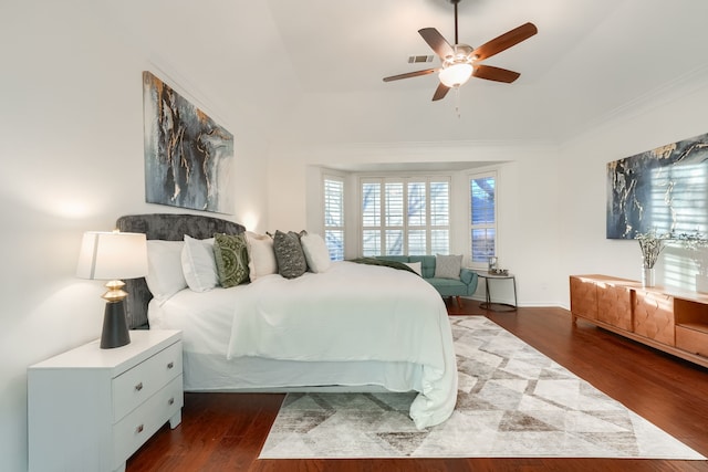 bedroom with a raised ceiling, ceiling fan, dark hardwood / wood-style flooring, and ornamental molding