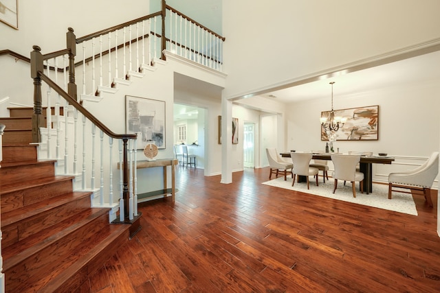 foyer entrance with a high ceiling, dark hardwood / wood-style floors, and a notable chandelier