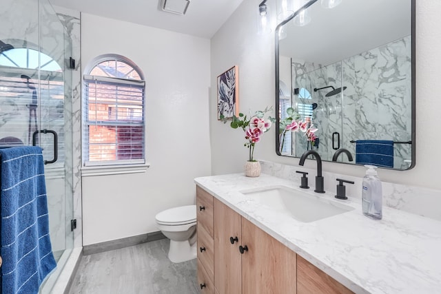 bathroom featuring vanity, toilet, and a shower with shower door