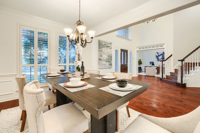 dining space featuring hardwood / wood-style flooring, ornamental molding, and an inviting chandelier