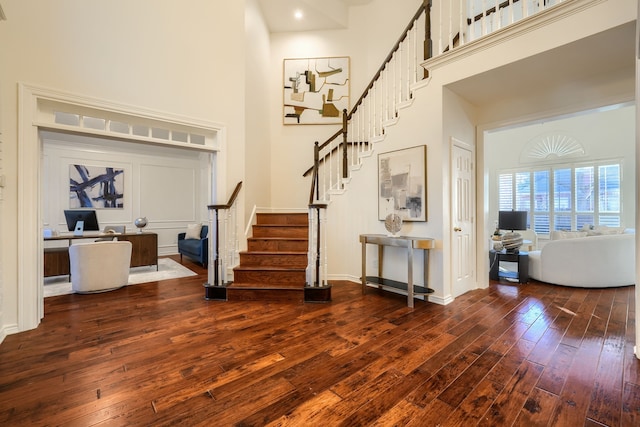 foyer featuring a towering ceiling and dark wood-type flooring