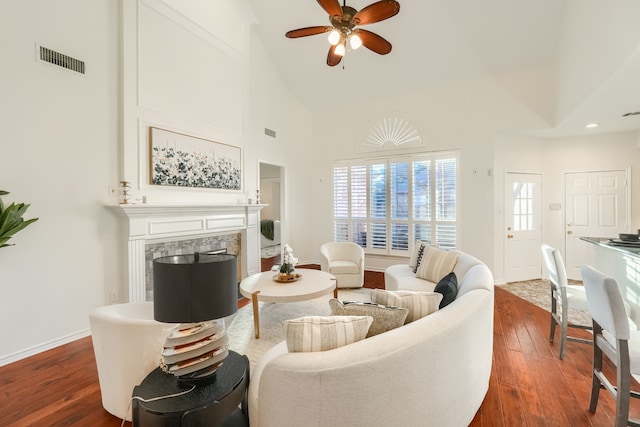 living room with a tiled fireplace, ceiling fan, high vaulted ceiling, and dark wood-type flooring