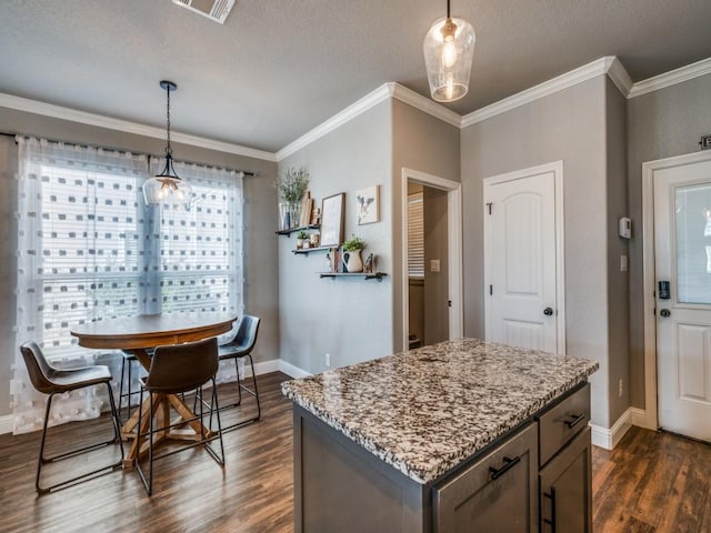 kitchen with dark hardwood / wood-style flooring, crown molding, a center island, and decorative light fixtures