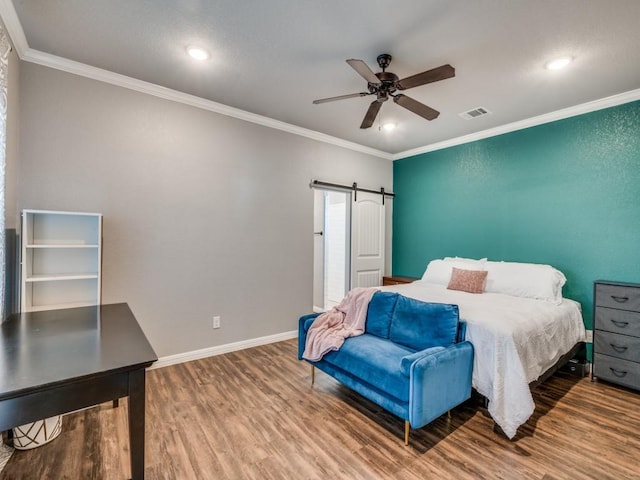 bedroom featuring hardwood / wood-style flooring, ceiling fan, a barn door, and crown molding