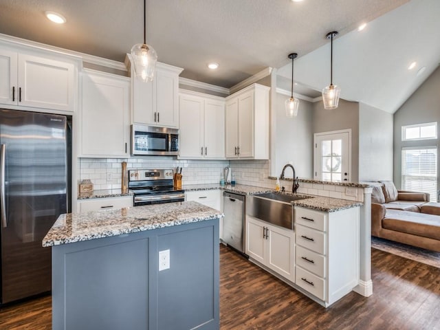 kitchen with kitchen peninsula, appliances with stainless steel finishes, sink, decorative light fixtures, and white cabinets