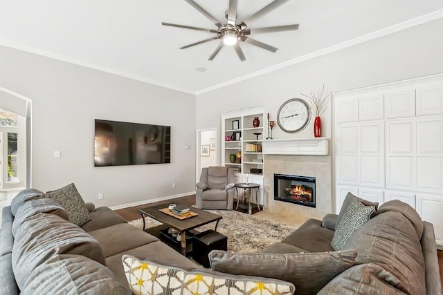 living room with hardwood / wood-style floors, ceiling fan, ornamental molding, and a tiled fireplace