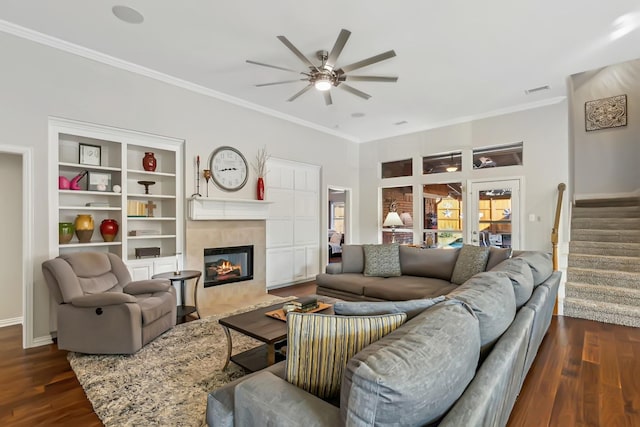 living room featuring a tiled fireplace, ceiling fan, dark wood-type flooring, and ornamental molding