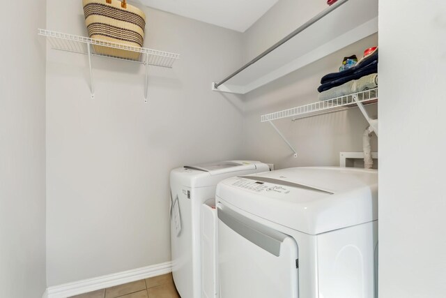 clothes washing area featuring washer and clothes dryer and light tile patterned floors