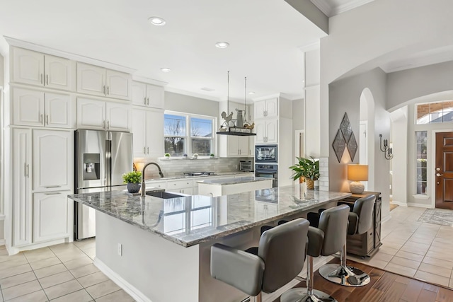 kitchen featuring pendant lighting, white cabinetry, sink, backsplash, and black appliances