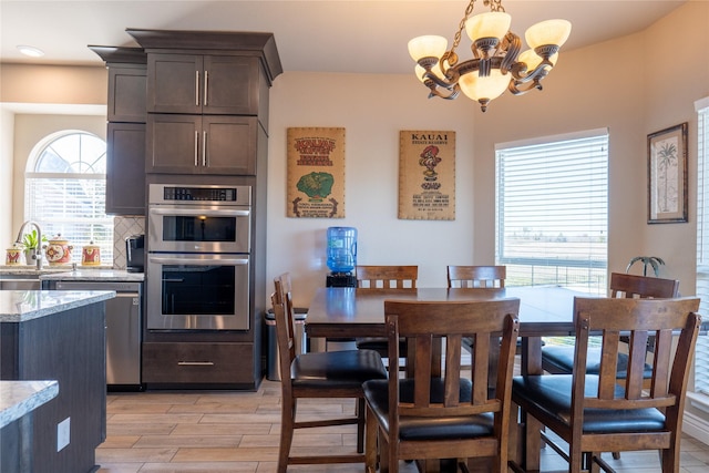 kitchen featuring light stone countertops, appliances with stainless steel finishes, dark brown cabinetry, an inviting chandelier, and hanging light fixtures