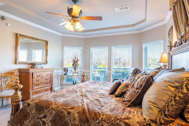 bedroom featuring ceiling fan, ornamental molding, and a tray ceiling