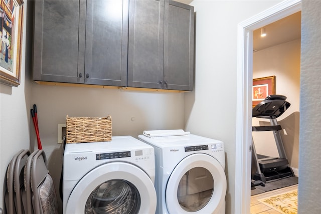 laundry room with washing machine and dryer, tile patterned flooring, and cabinets