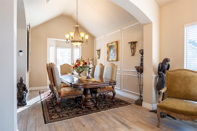 dining space featuring a notable chandelier, light wood-type flooring, and lofted ceiling