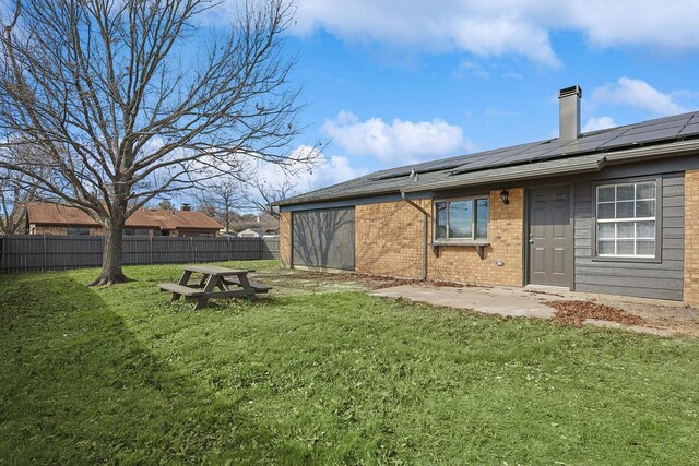 rear view of property with a yard and solar panels