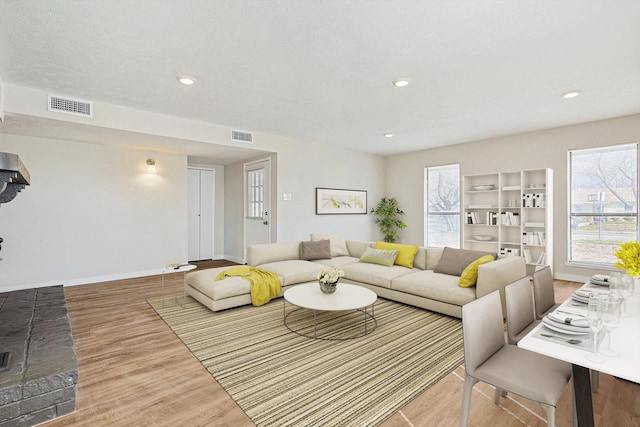 living room featuring wood-type flooring, a textured ceiling, and a wealth of natural light